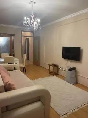 Dnevna soba sa garniturom, TV-om i trpezarijskim stolom u pozadini.