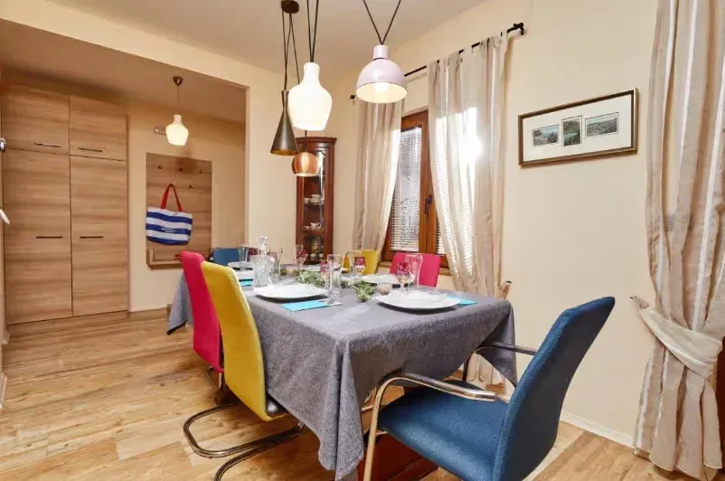 Dining area with a table, colorful chairs, and hanging lamps.