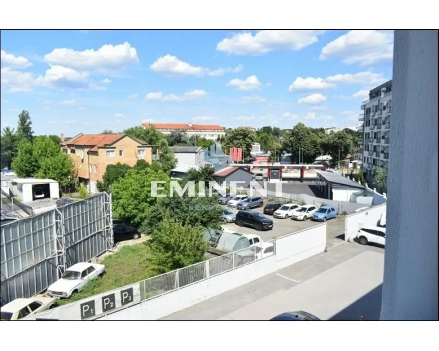 View from the window overlooking surrounding buildings, parking lot, and greenery.