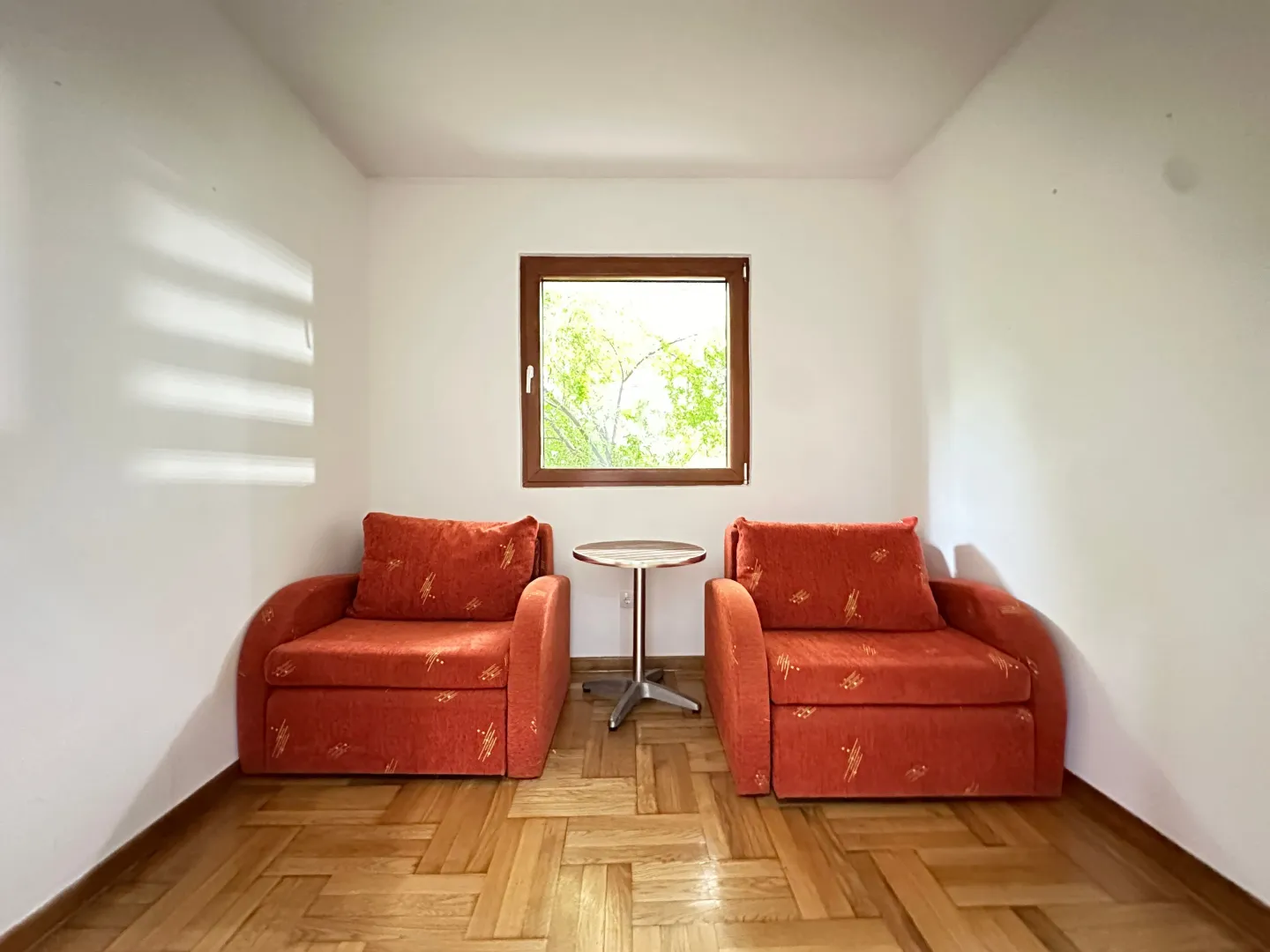 Living room with two red armchairs and a small table under the window.