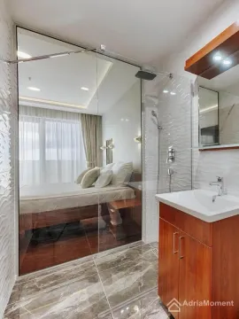 Bathroom with a vanity sink and a glass partition overlooking the bedroom. - image 7