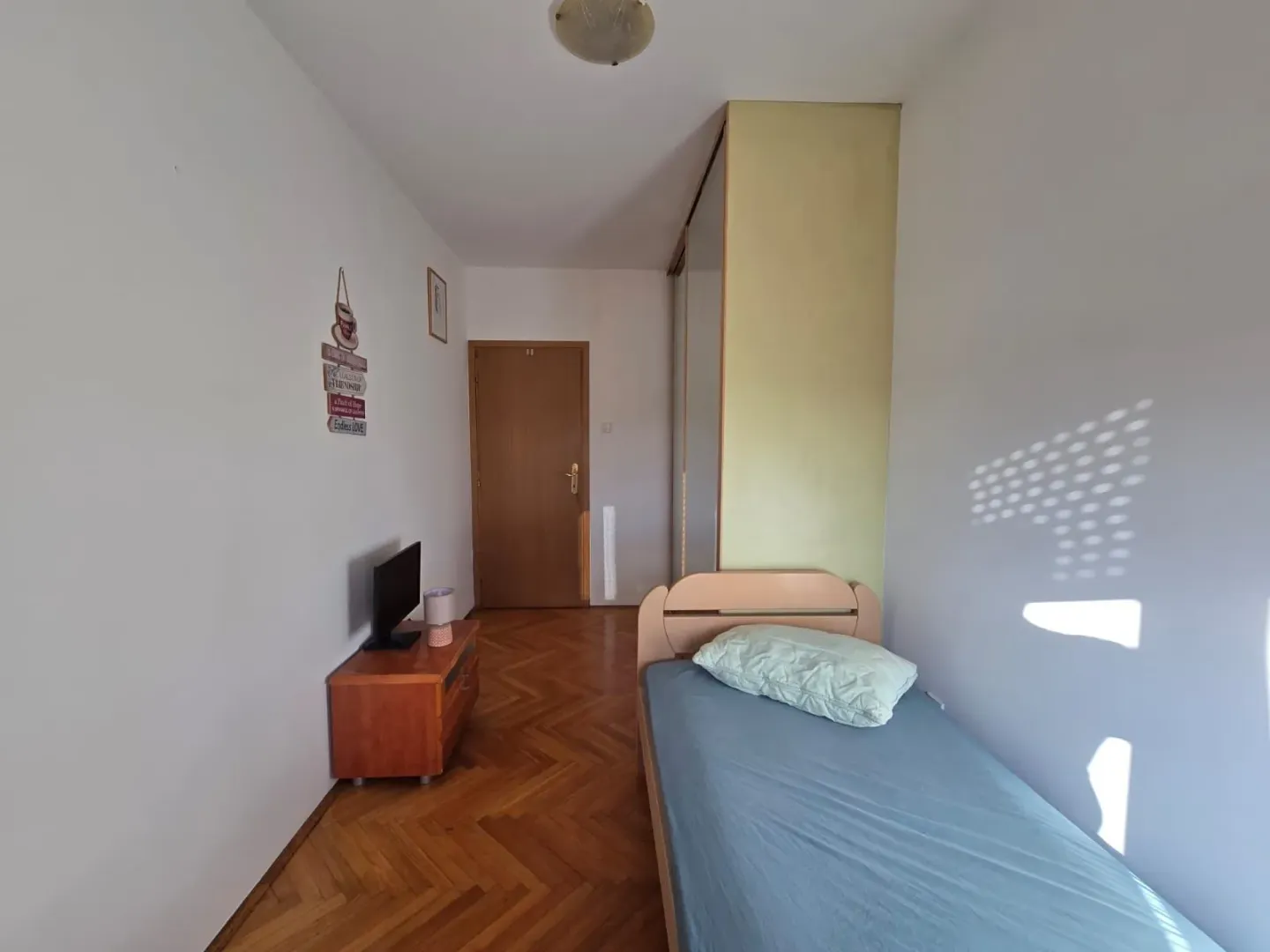 Single bedroom with a wardrobe and parquet flooring.