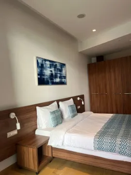 Furnished bedroom with a double bed, wooden wardrobe, and an art painting on the wall. - image 4