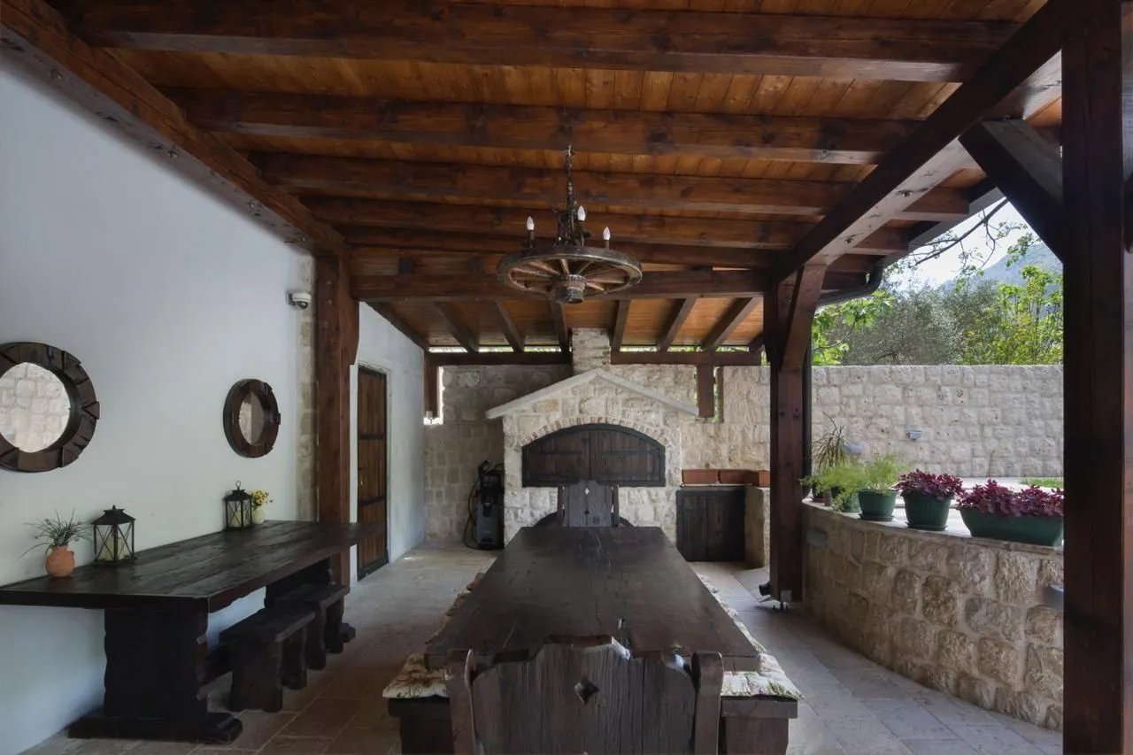 Spacious covered terrace with solid wood furniture and a stone fireplace.