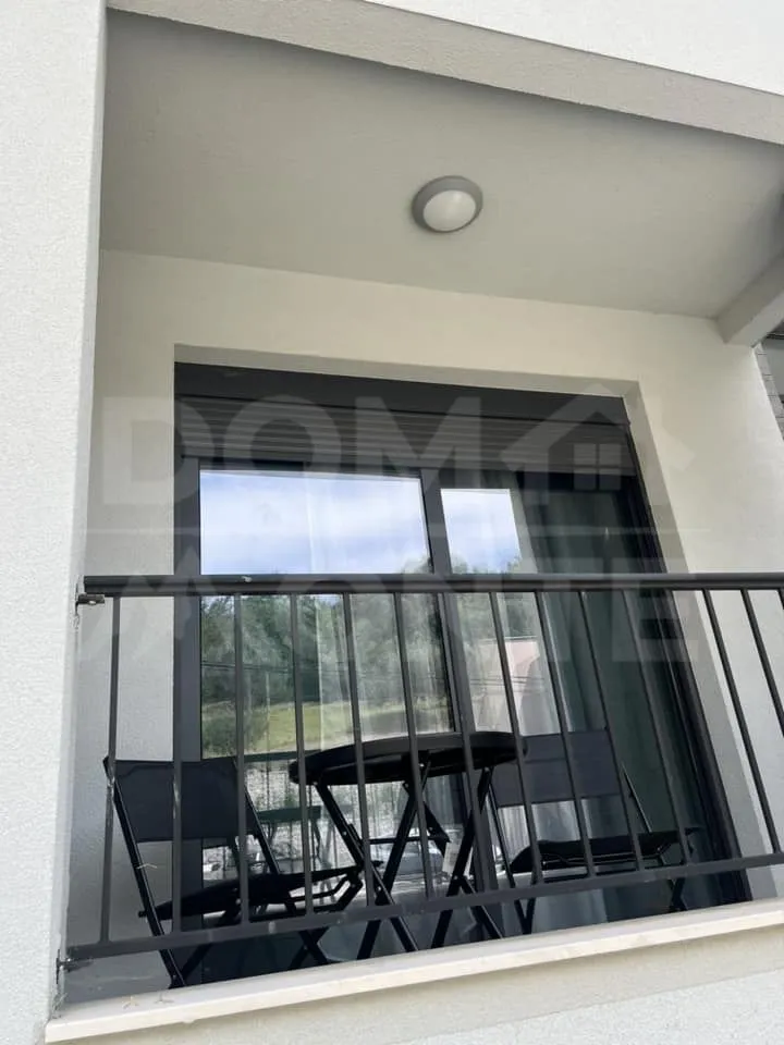 Manji namješteni balkon sa crnom ogradom i garniturom za sjedenje.
