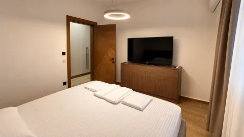 Furnished bedroom with a double bed, TV unit, and an open door leading to the hallway. - image 12