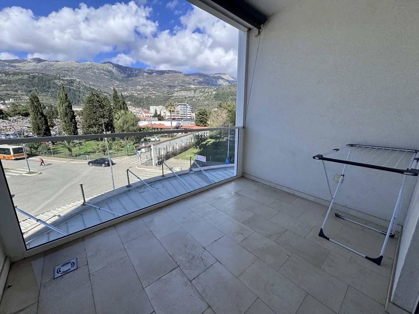 Natkriveni balkon sa staklenom ogradom i pogledom na planine i grad.