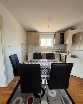 Dining area with a table and black chairs and kitchen units in the background. - image 7