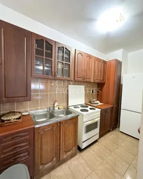 Kuhinja opremljena drvenim elementima, šporetom i frižiderom. - image 8