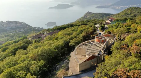 Pogled iz vazduha na objekat u izgradnji okružen zelenilom sa pogledom na more. - image 3
