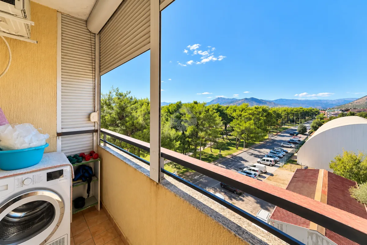 Zastakljeni balkon sa veš mašinom i pogledom na prirodu i okolinu.