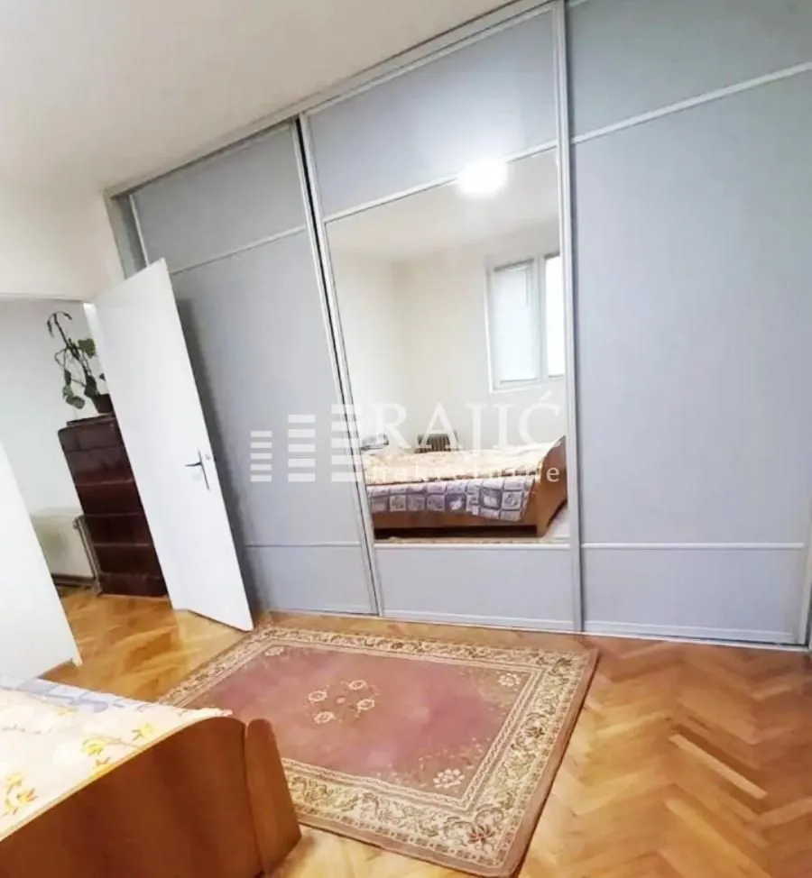 Bedroom with a large mirrored wardrobe and parquet flooring.