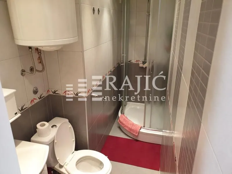 Small bathroom with a shower cabin, toilet, and water heater.