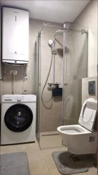 Modernly equipped bathroom with a shower cabin, toilet, washing machine, and water heater. - image 8