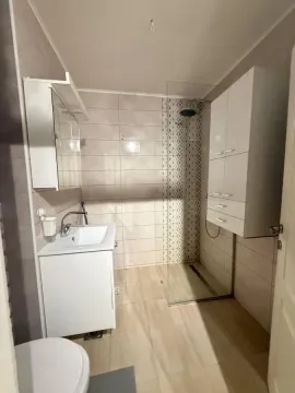 Moderno opremljeno kupatilo sa tuš kabinom, umivaonikom i belim elementima. - image 16