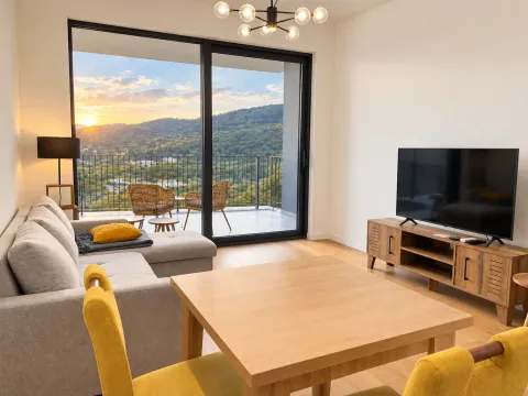 Modern living room with a sofa, TV, and access to a terrace with a nature view. - image 3