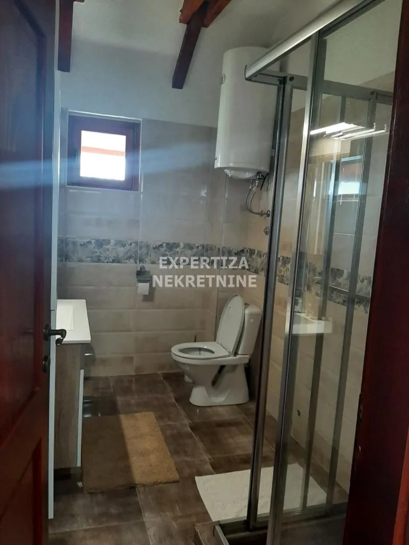 Manje kupatilo sa tuš kabinom, WC šoljom i bojlerom.