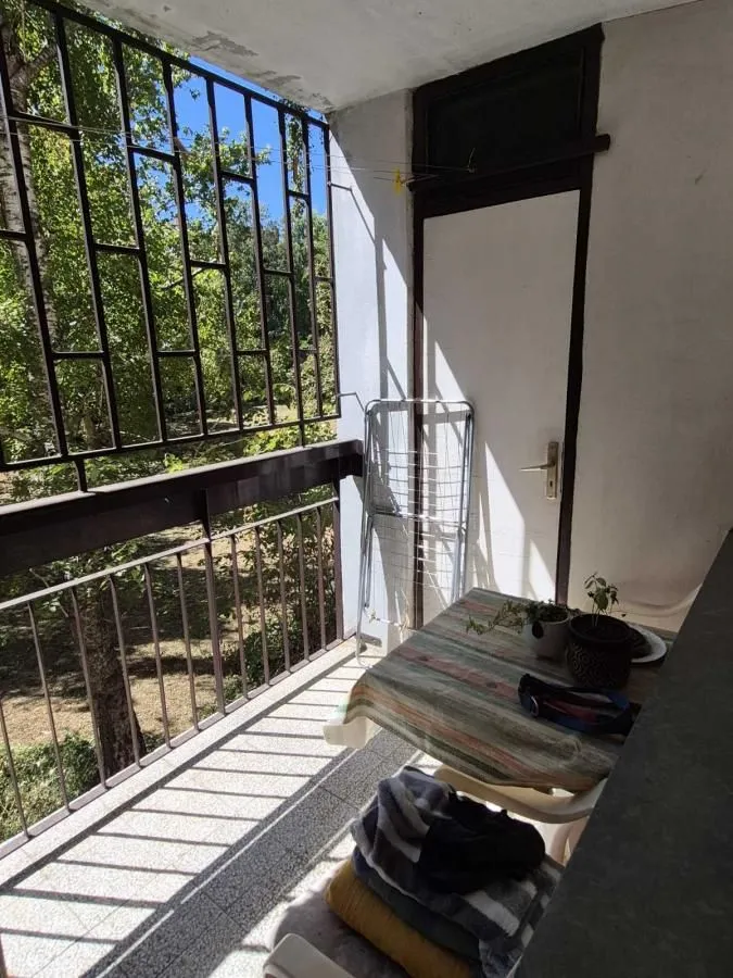 Manji natkriveni balkon sa metalnom ogradom i stolom.
