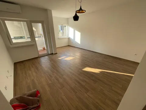Prazna soba sa drvenim podom, bijelim zidovima i izlazom na balkon. - image 2