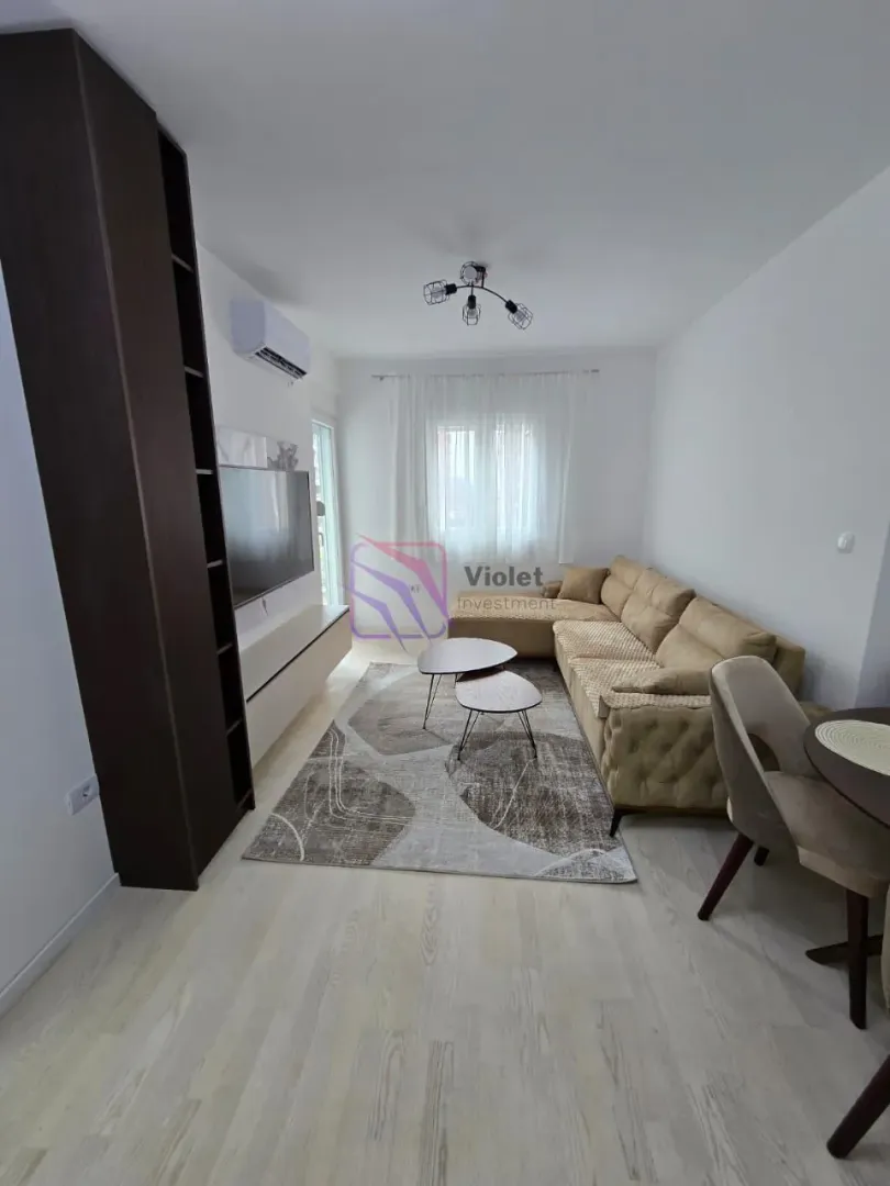 Living room with sofa, TV and dining table.