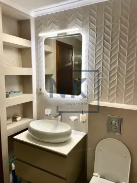 Modern bathroom with a washbasin, illuminated mirror, and built-in shelves. - image 10