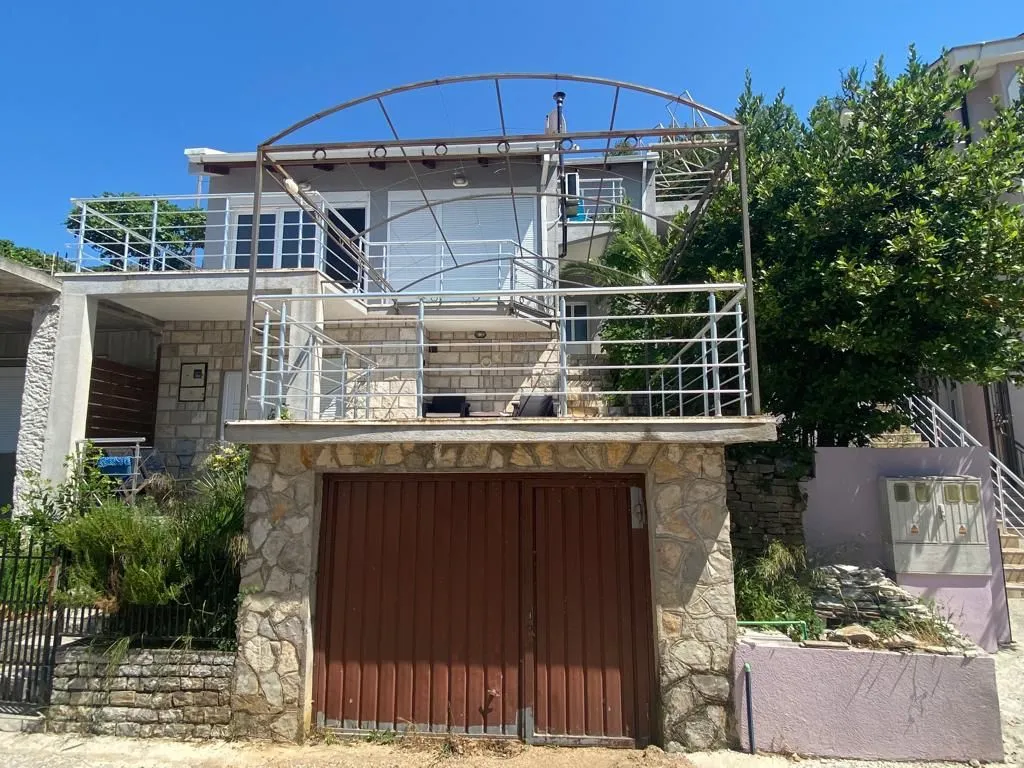 Spoljašnji izgled kuće sa terasom i garažom.