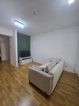 Dnevna soba sa svijetlom garniturom, TV komodom i drvenim podom. - image 5