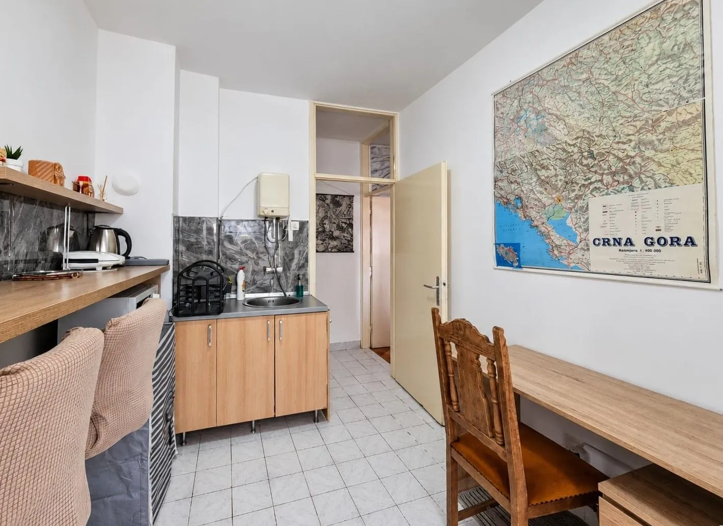 Smaller kitchen with a sink, desk and chairs.