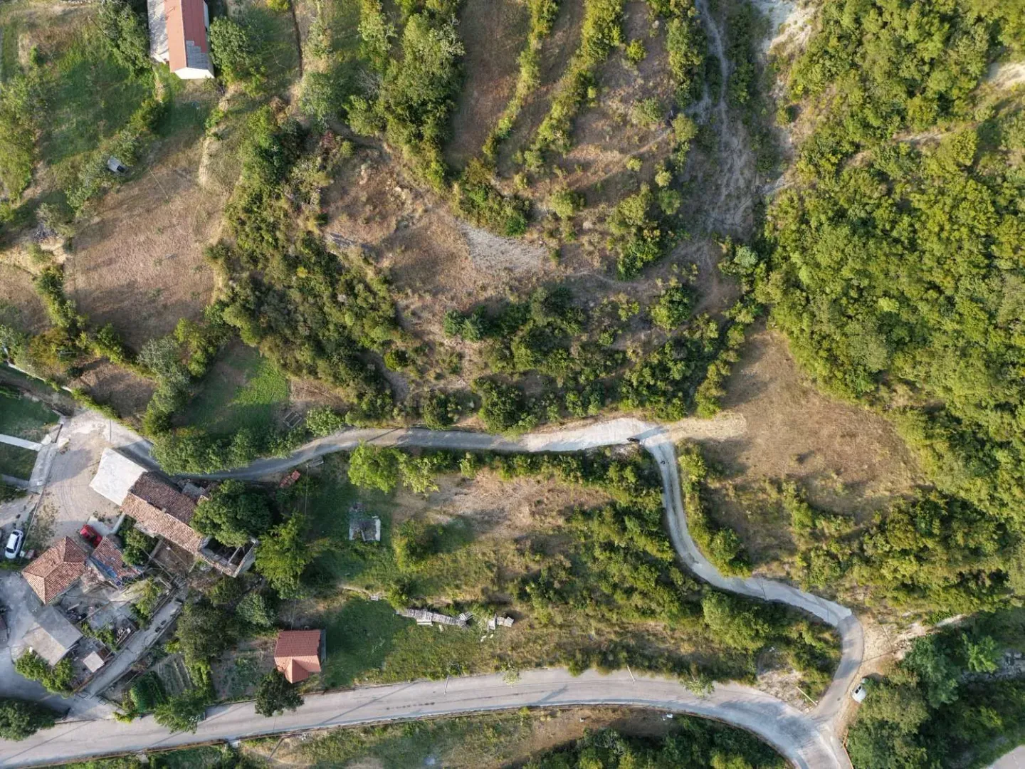 Pogled iz vazduha na zemljište sa putem i okolnim zelenilom.