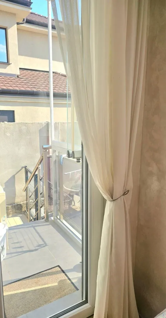 Balkonska vrata sa svijetlom zavjesom i pogledom na terasu.