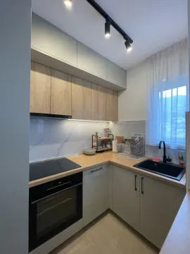 Small equipped kitchen with wooden elements and built-in appliances. - image 9