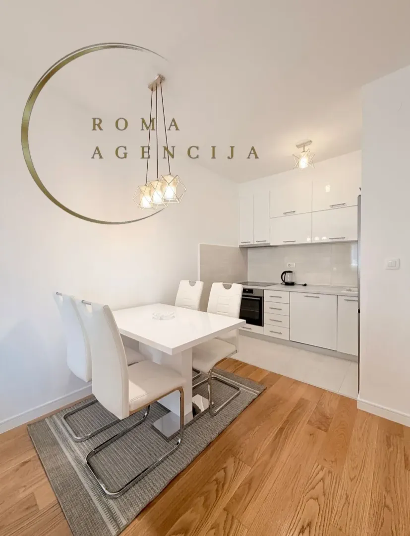 Modern white kitchen with a dining area and hardwood floors.