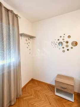 Part of a room with a wooden floor, a window with a curtain, and a small bedside table. - image 5
