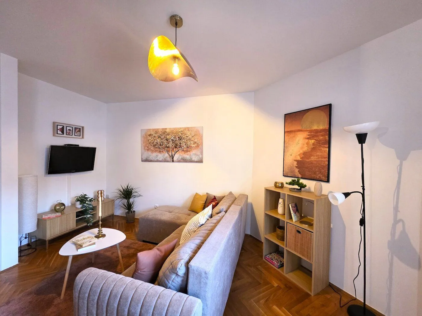 Comfortable living room with a sectional sofa, TV, and shelving unit.