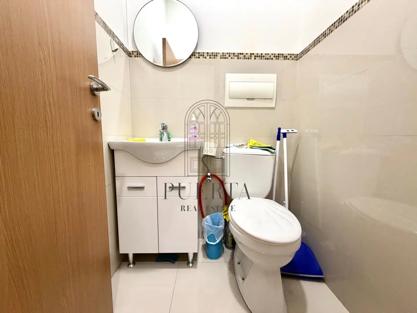 Smaller bathroom with a sink, toilet bowl, and mirror.
