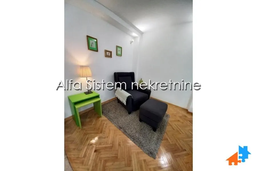 Smaller living room with an armchair, ottoman and green side table.