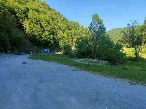 Pogled na zemljište pored puta sa šumovitim brdom u pozadini. - image 3