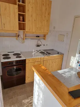Small kitchen with wooden cabinets and a cooker. - image 4