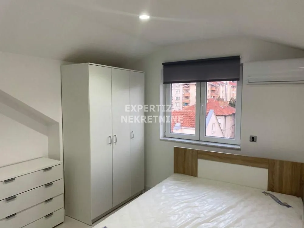 Furnished bedroom with a double bed, wardrobe, and window.