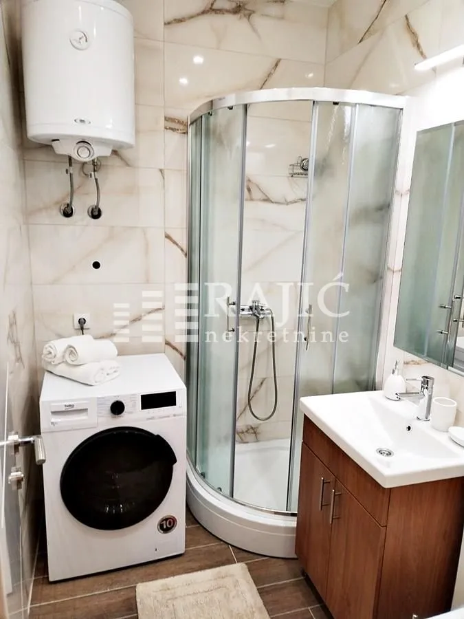 Bathroom with a shower cabin, washbasin, and washing machine.