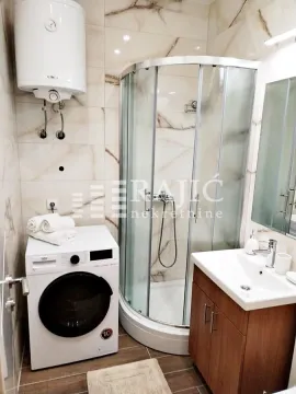 Bathroom with a shower cabin, washbasin, and washing machine. - image 7