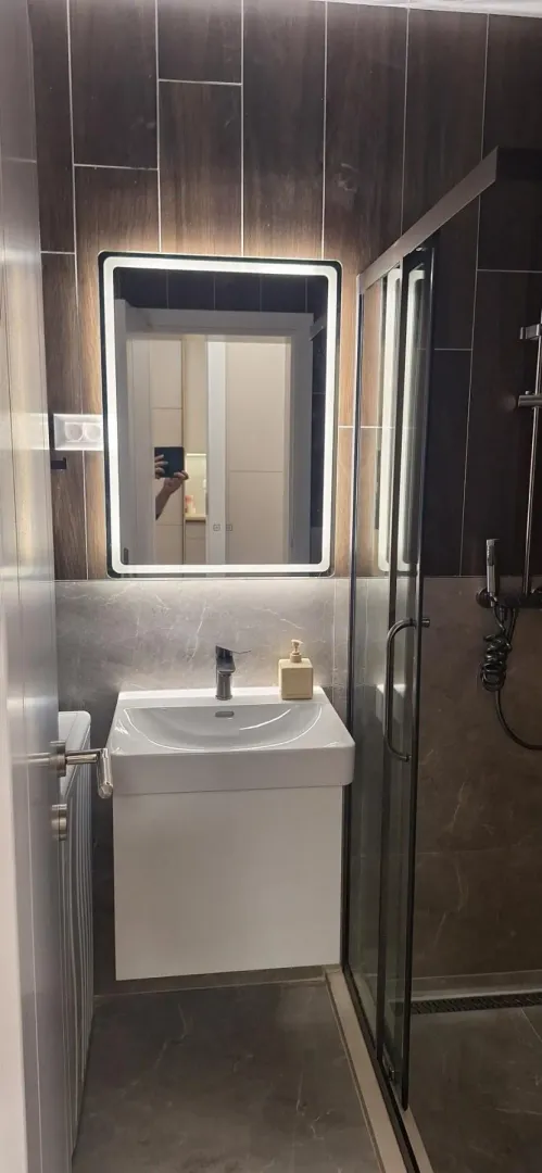 Moderno opremljeno kupatilo sa umivaonikom i tuš kabinom.