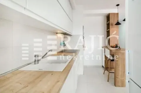 Modern kitchen with white cabinetry and a wooden bar counter. - image 6