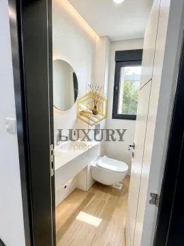 Modernly equipped bathroom with a washbasin, toilet bowl, and window. - image 2