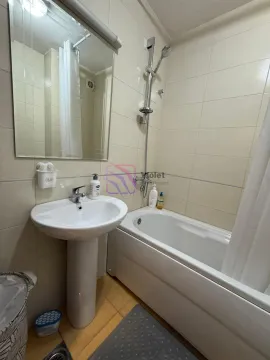 Bathroom with a washbasin, mirror, and bathtub with a shower. - image 10