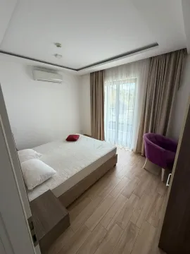 Svjetla spavaća soba sa bračnim krevetom i ljubičastom foteljom. - image 3