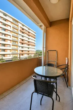 Covered balcony furnished with a glass table and black chairs. - image 9