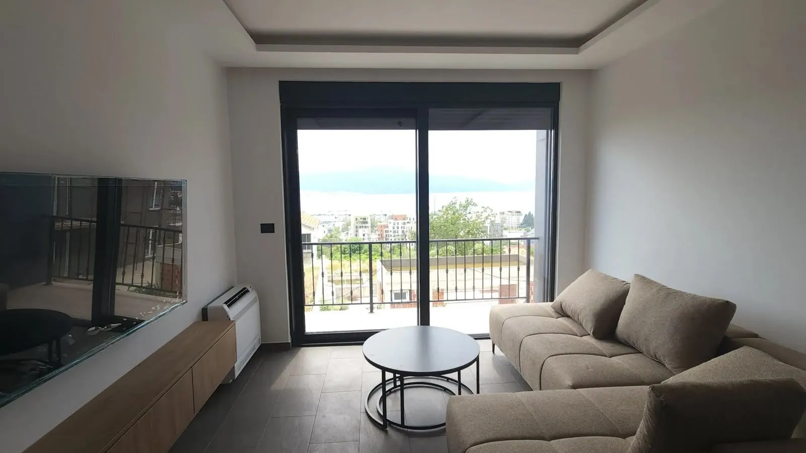 Living room with sofa, TV, and access to a terrace with a view.