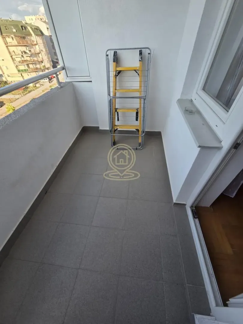Smaller tiled balcony with a clothes dryer and a view of surrounding buildings.
