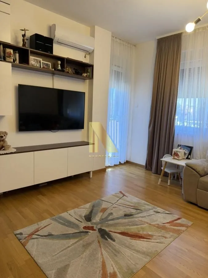 Dnevna soba sa televizorom, nameštajem i tepihom.